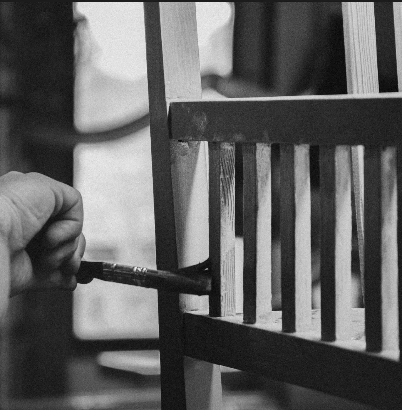 Hands restoring a wooden chair with a brush — craftsmanship in process