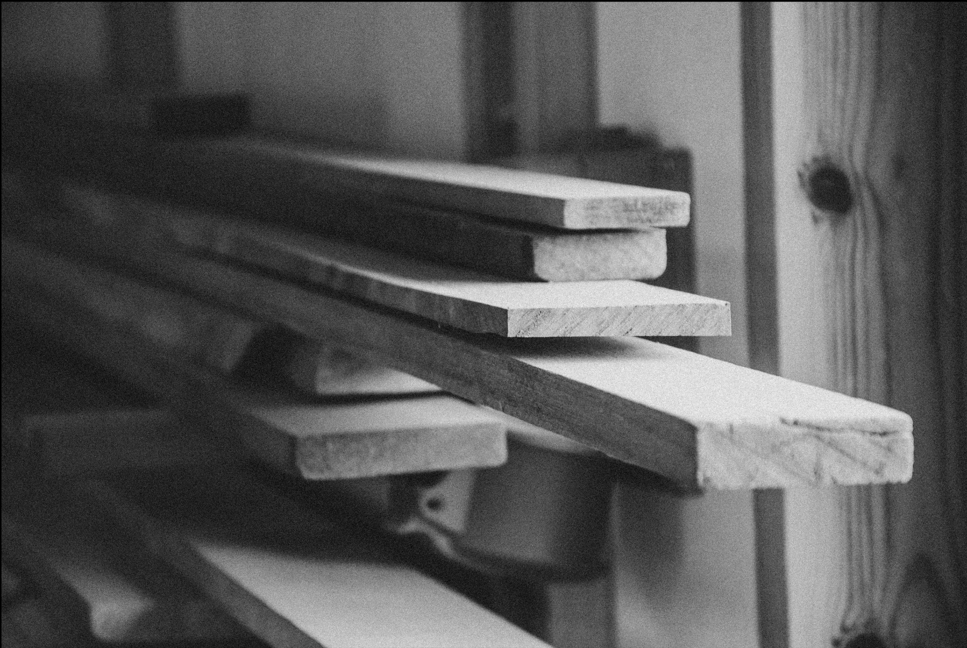 Stacked raw timber planks in soft black and white light